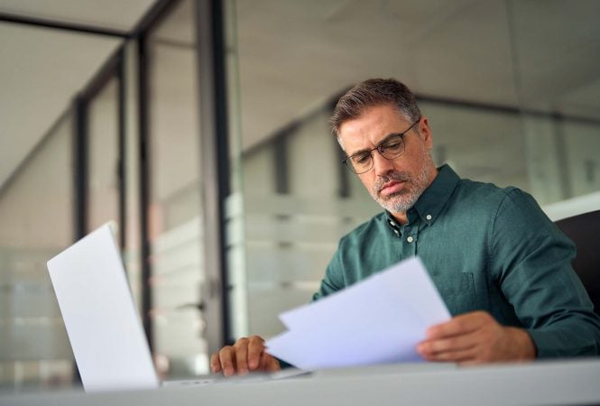 **Alt text (13 words):** Business owner reviewing exit documents at desk for Ascend Business Brokers listing.