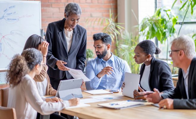 Team of diverse professionals collaborating in a meeting room with planning board, supported by Ascend Business Brokers.