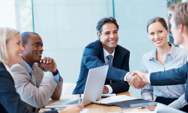 Ascend Business Brokers facilitating a business sale agreement between two parties during a meeting