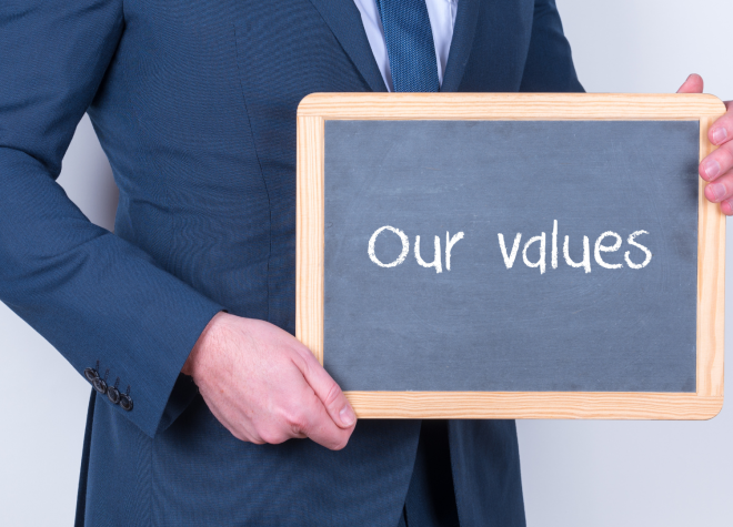 Man in suit holding chalkboard with “Our values” for Ascend Business Brokers branding.