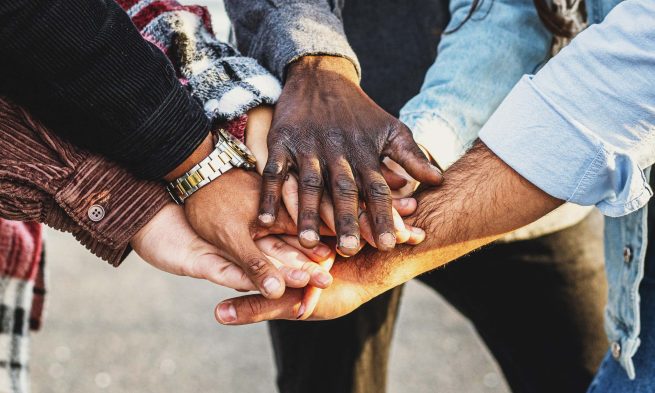 Team members placing hands together to represent unity and communication at Ascend Business Brokers